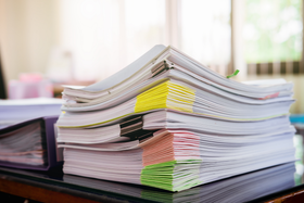 Hand holding a gold-tipped fountain pen writing on tan paper.
