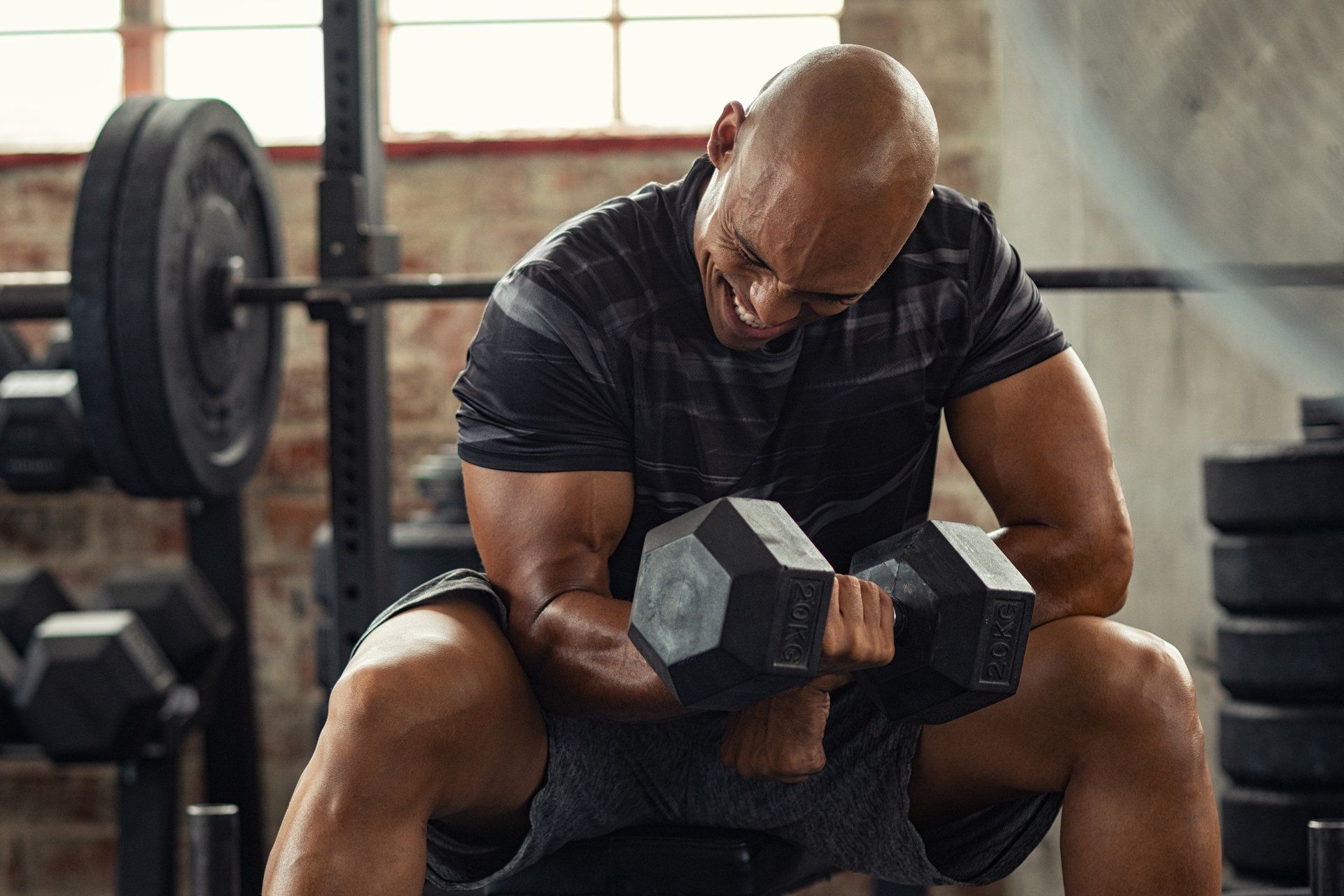 a man is sitting on a bench in a gym holding a dumbbell .