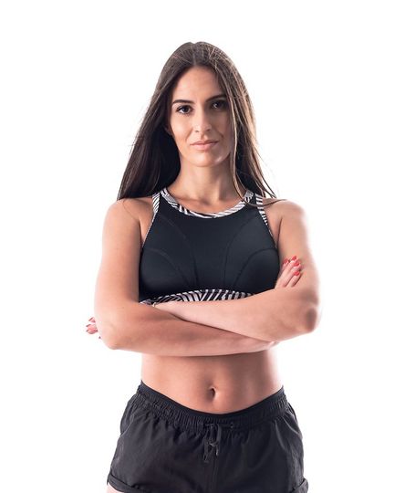 a woman in a black sports bra and shorts is standing with her arms crossed .