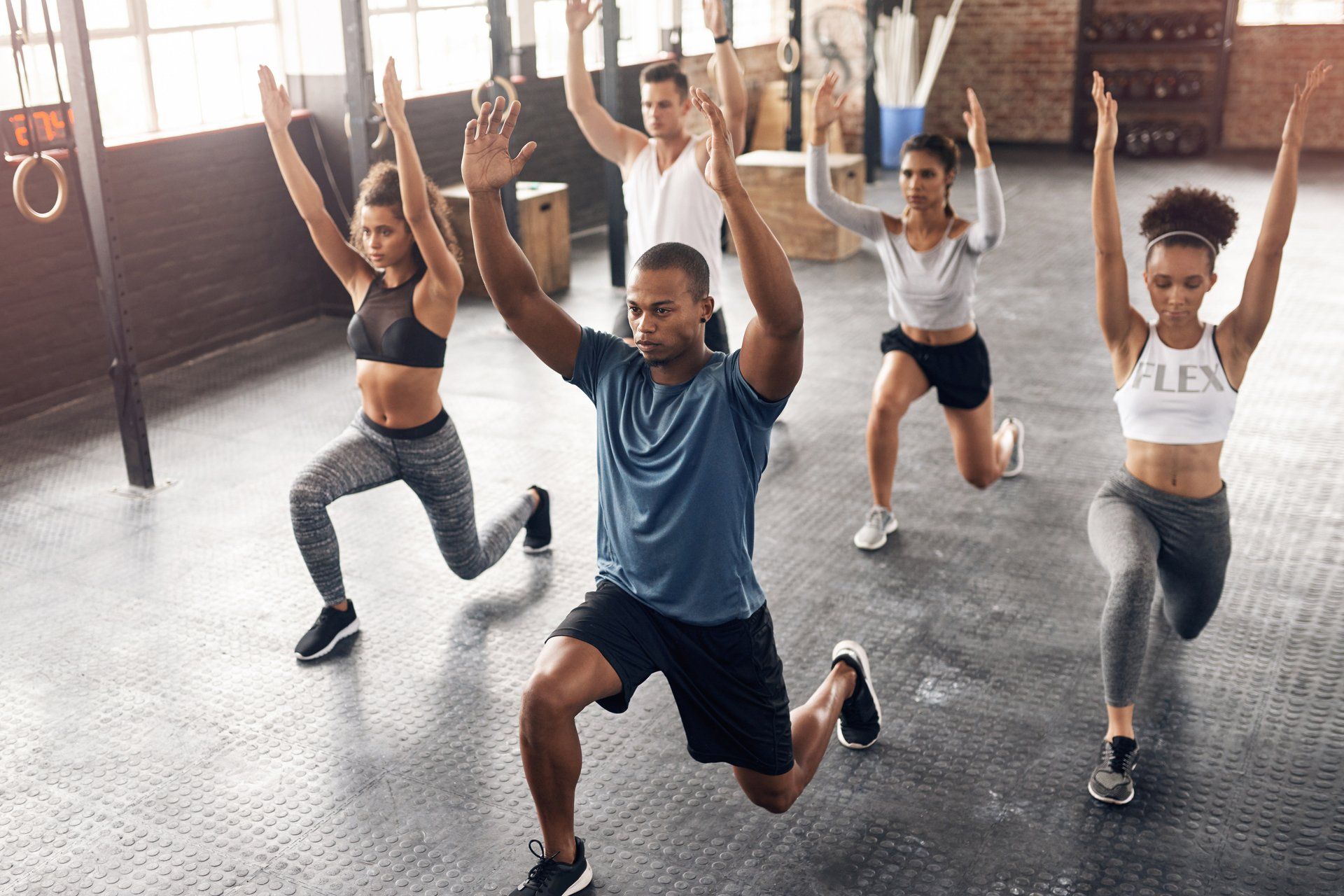 a group of people are doing stretching exercises in a gym .