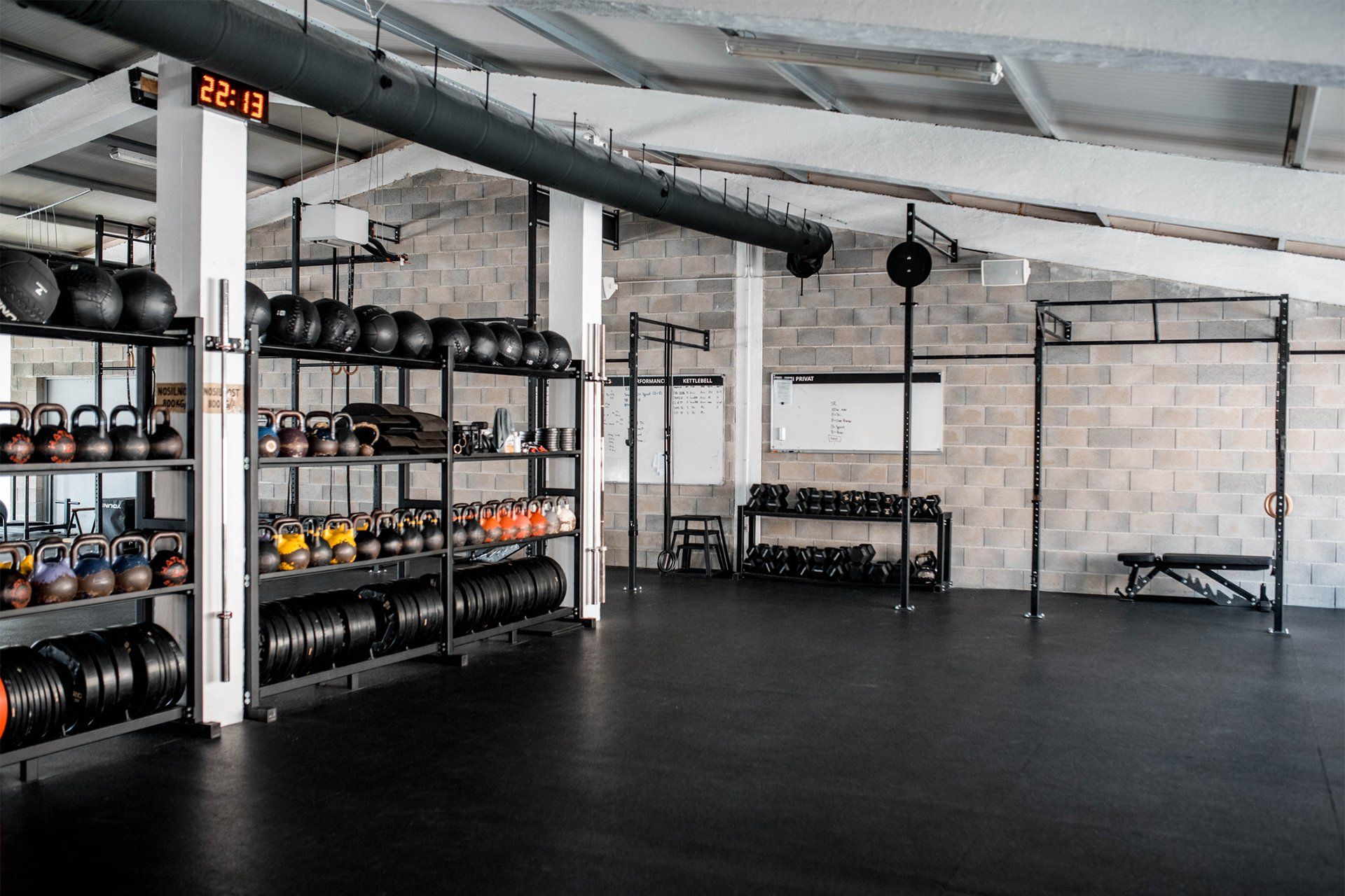 a large empty gym with a lot of dumbbells on shelves .