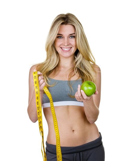 a woman is holding an apple and measuring her waist with a tape measure