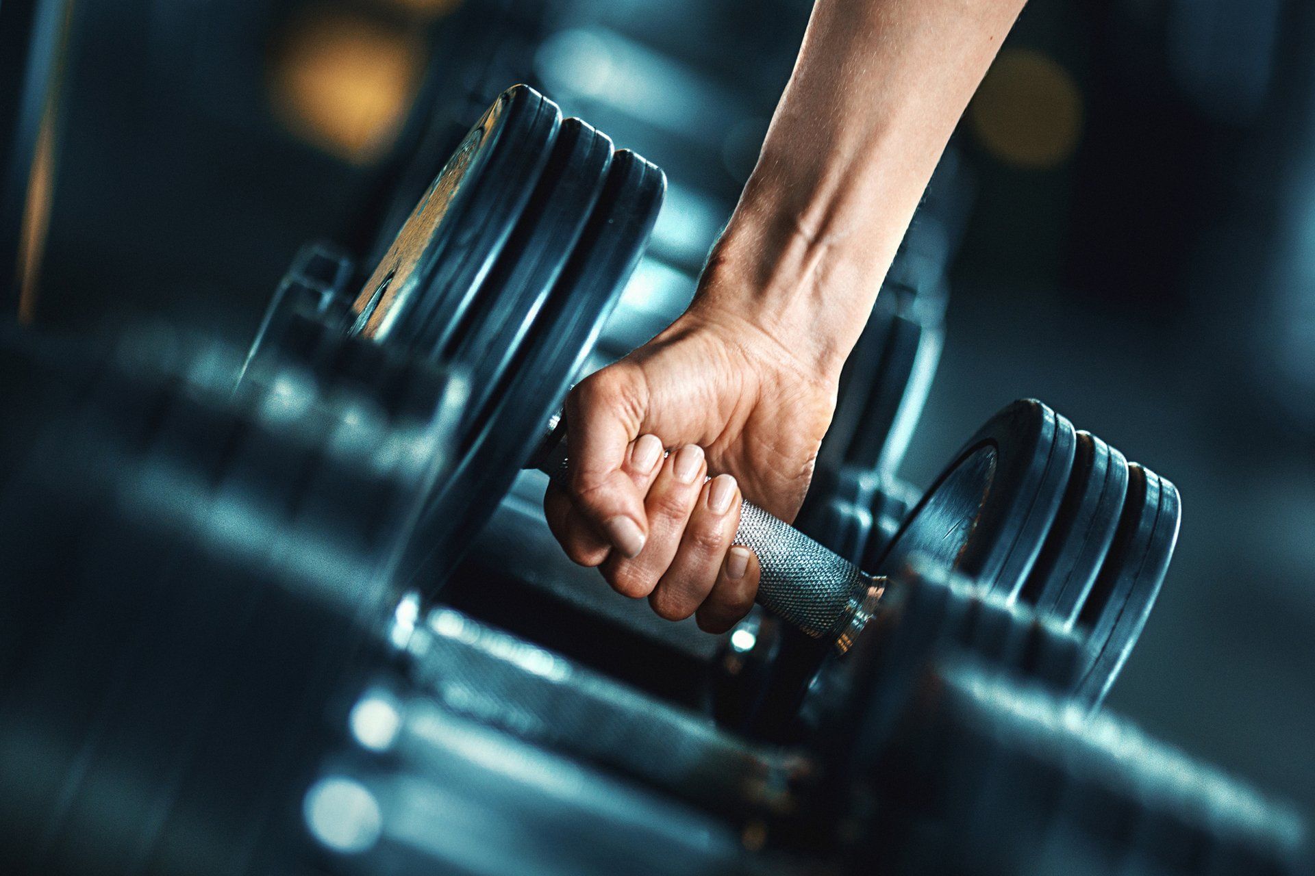 a person is holding a dumbbell in their hand in a gym .