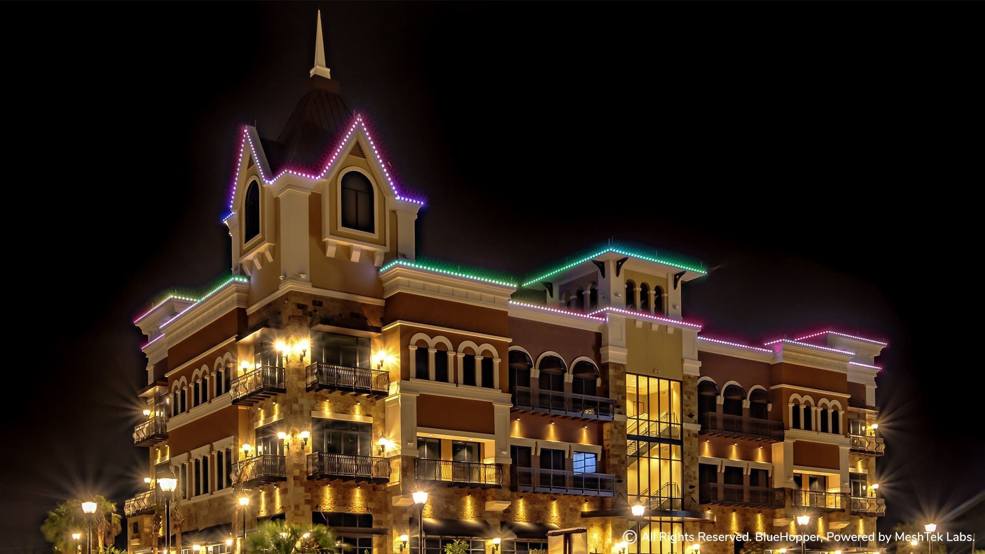 A large building with christmas lights on it is lit up at night.