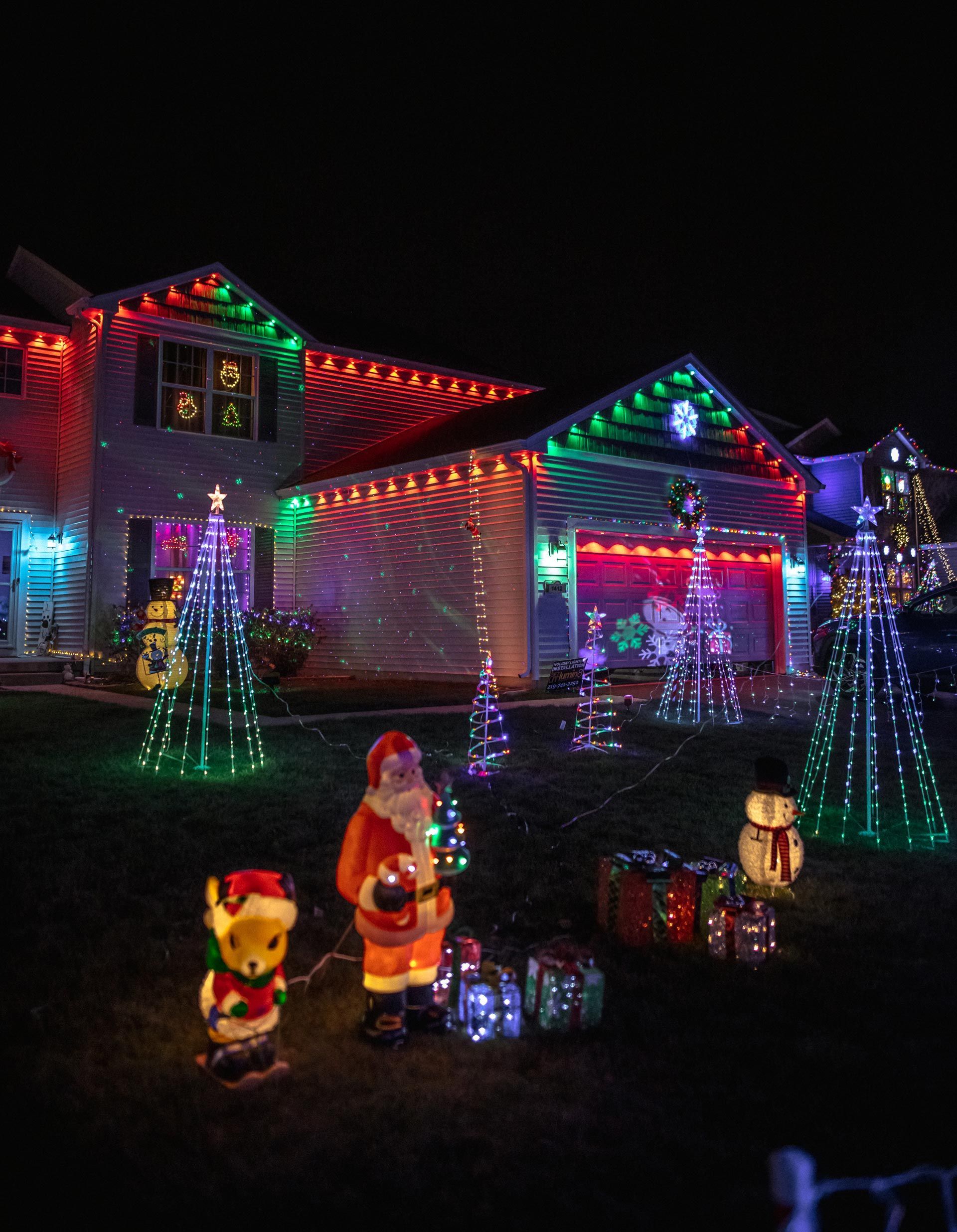 A house is decorated with christmas lights and decorations at night.