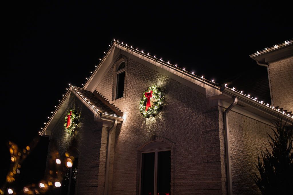 A house is decorated with christmas lights and wreaths at night.