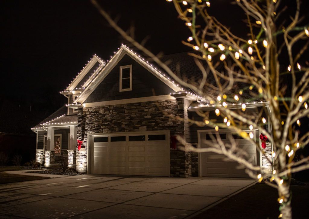 A house decorated with christmas lights at night with a tree in front of it.