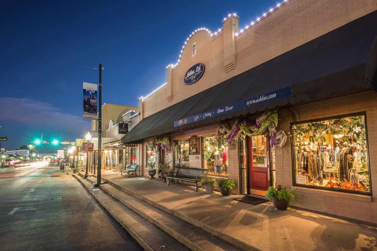 A row of stores are lined up on a city street at night.