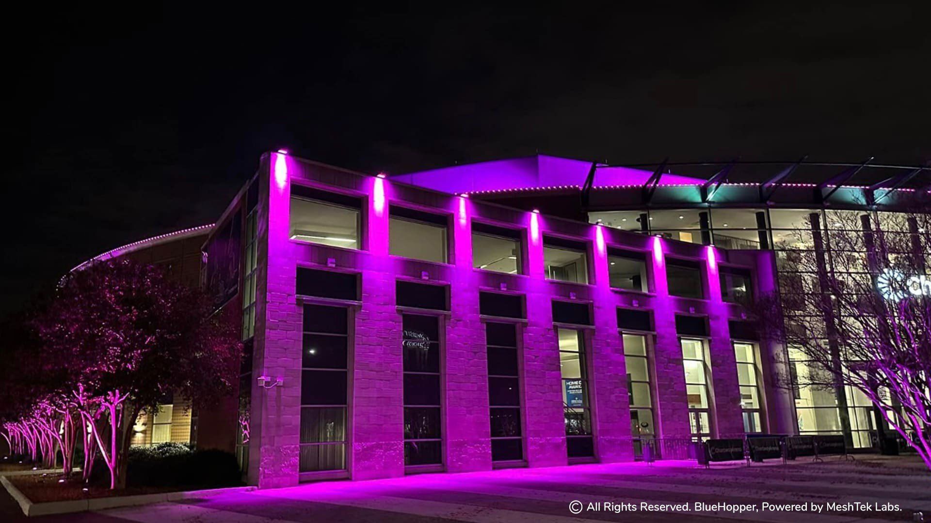A large building is lit up with purple lights at night.