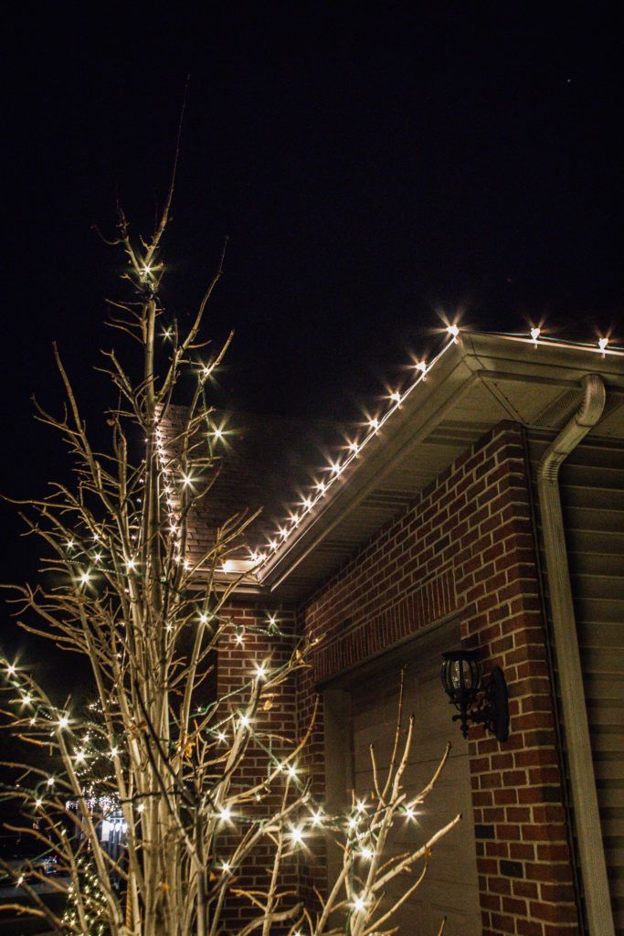 A house with christmas lights on the side of it at night.