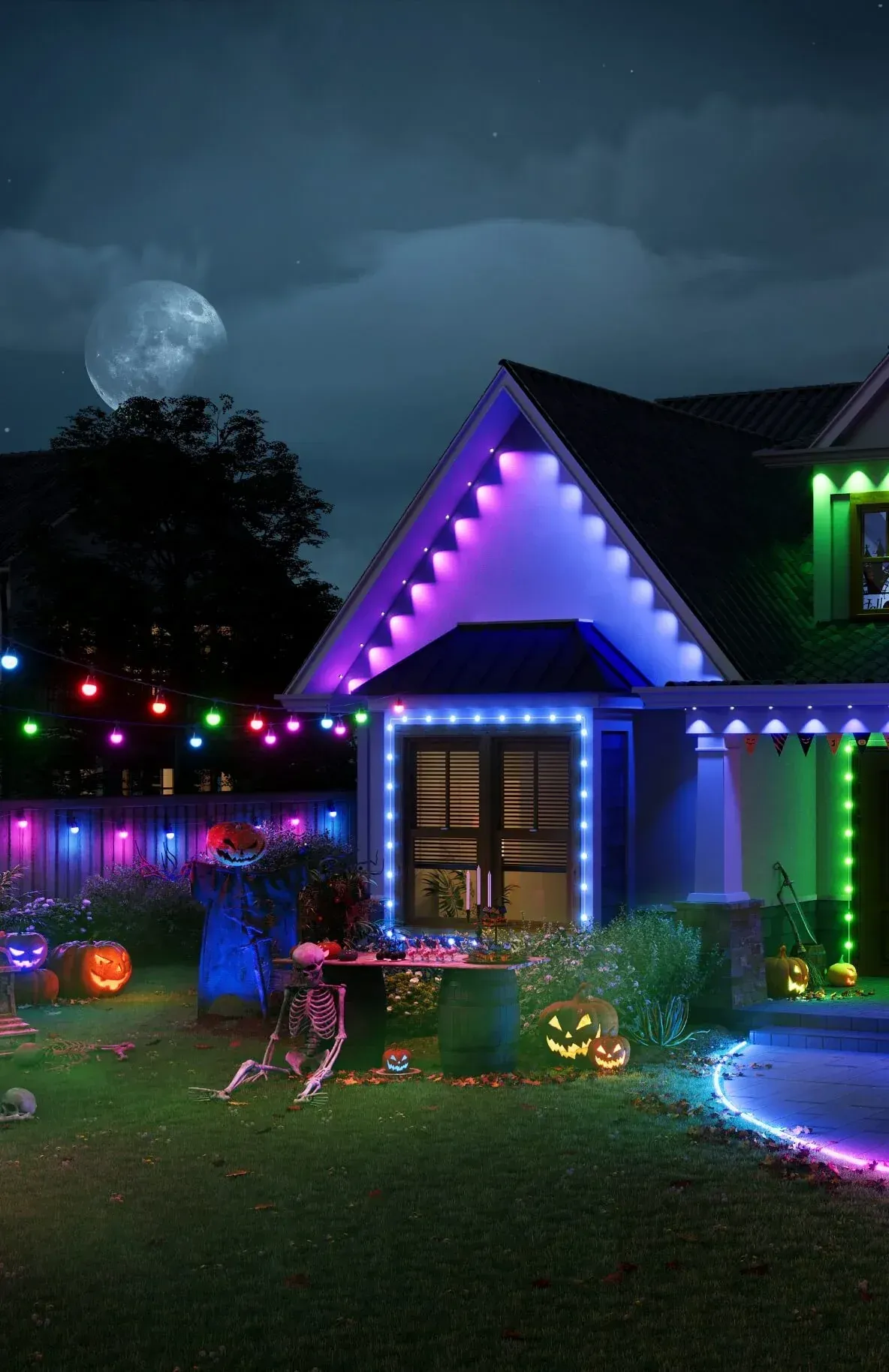 A house is decorated with halloween lights and pumpkins at night.
