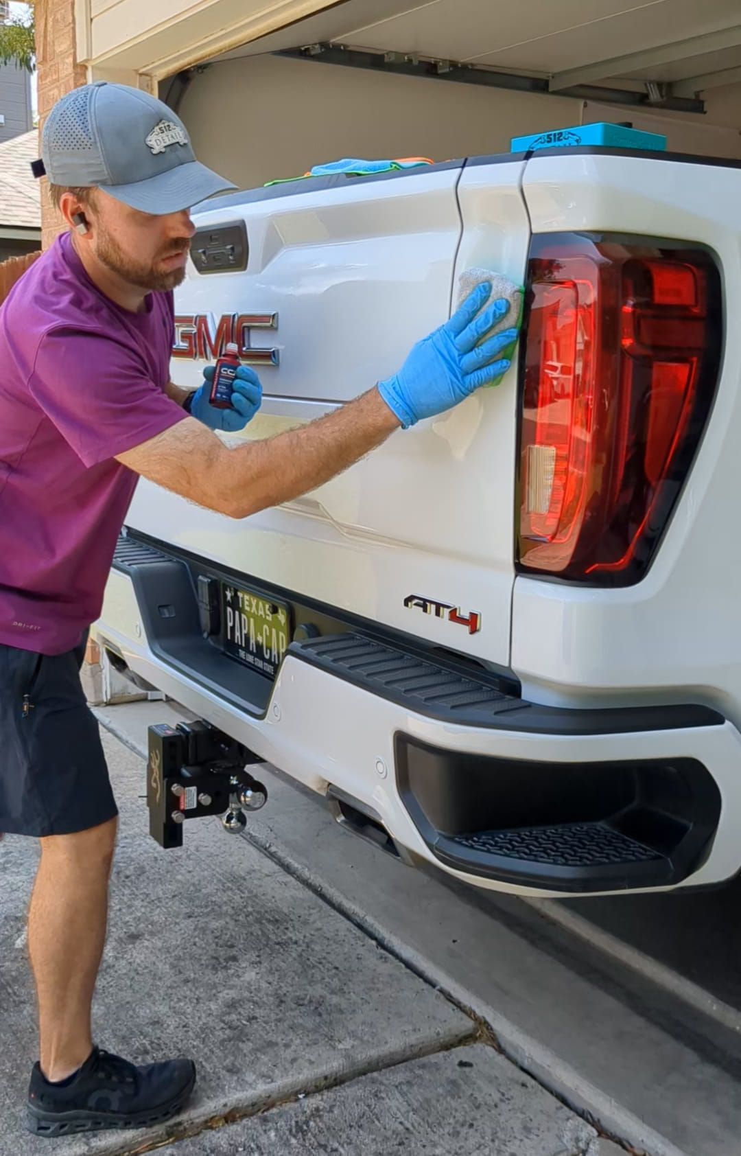 A man is cleaning the tail light of a white truck.