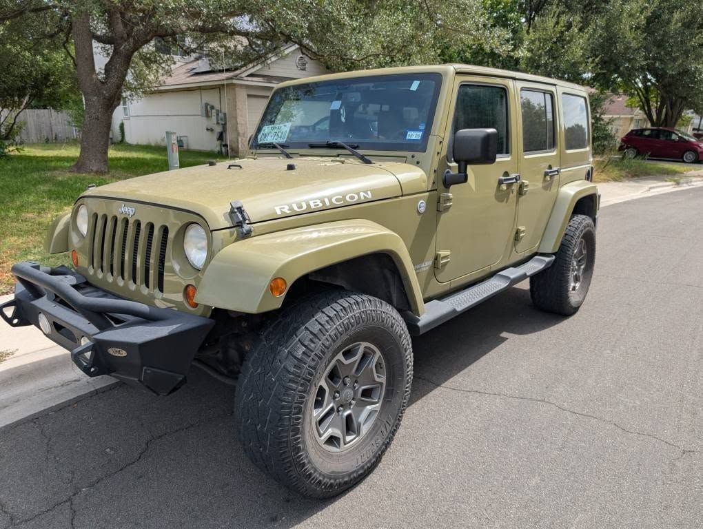 Olive green Jeep Wrangler Rubicon parked on a residential street.