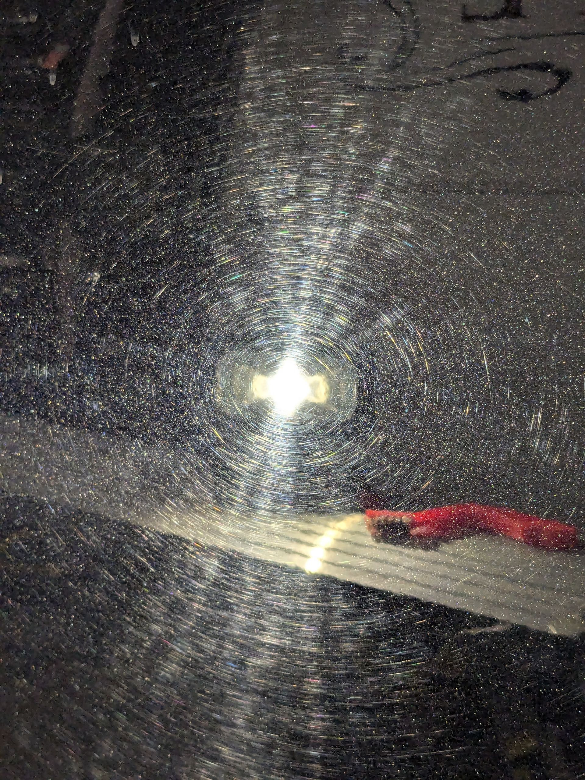 A close up of a shiny surface with a light shining through it