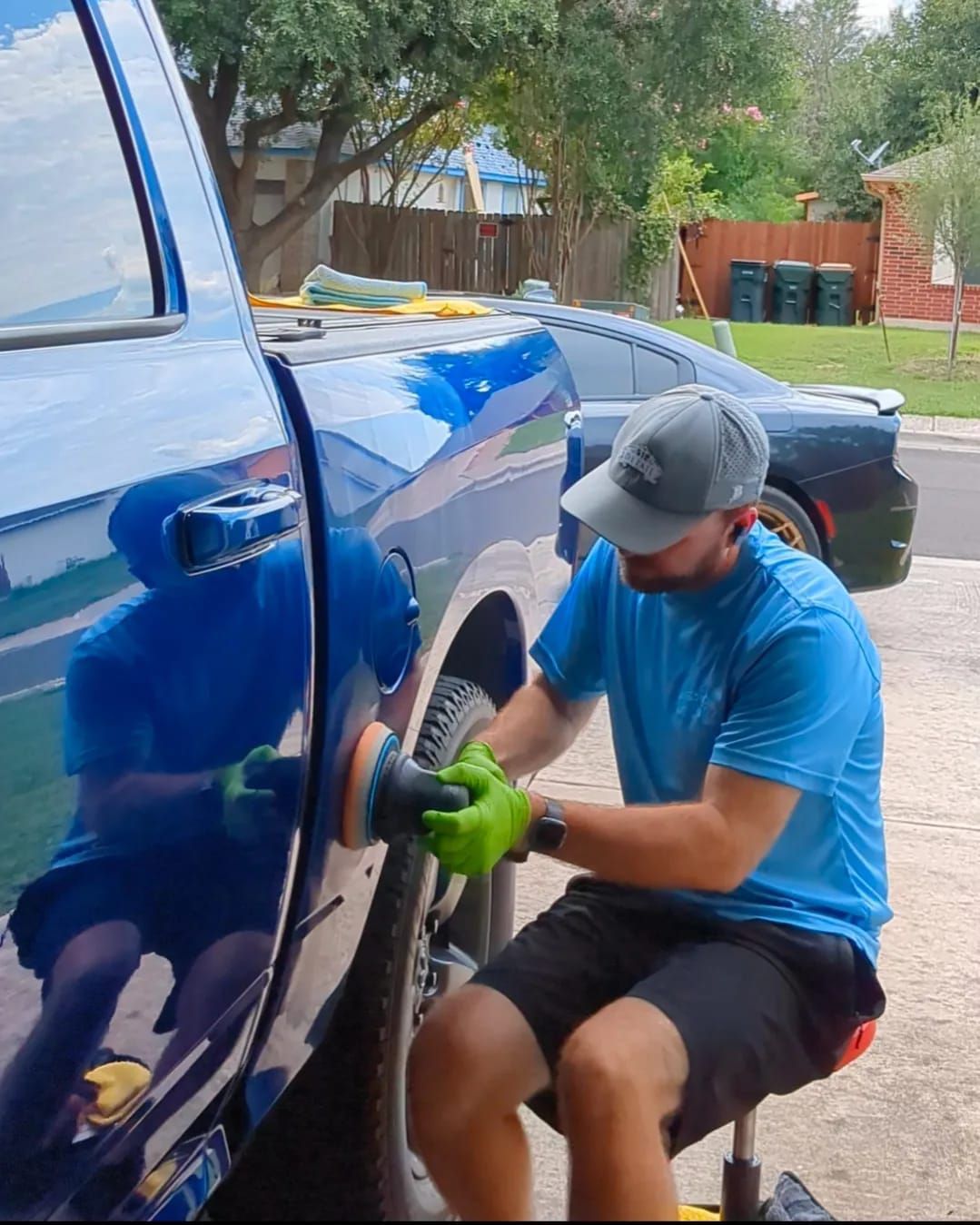 A man in a blue shirt is polishing a blue truck