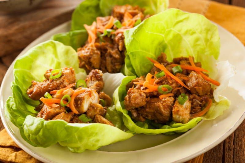 A white plate topped with lettuce wraps filled with meat and vegetables.