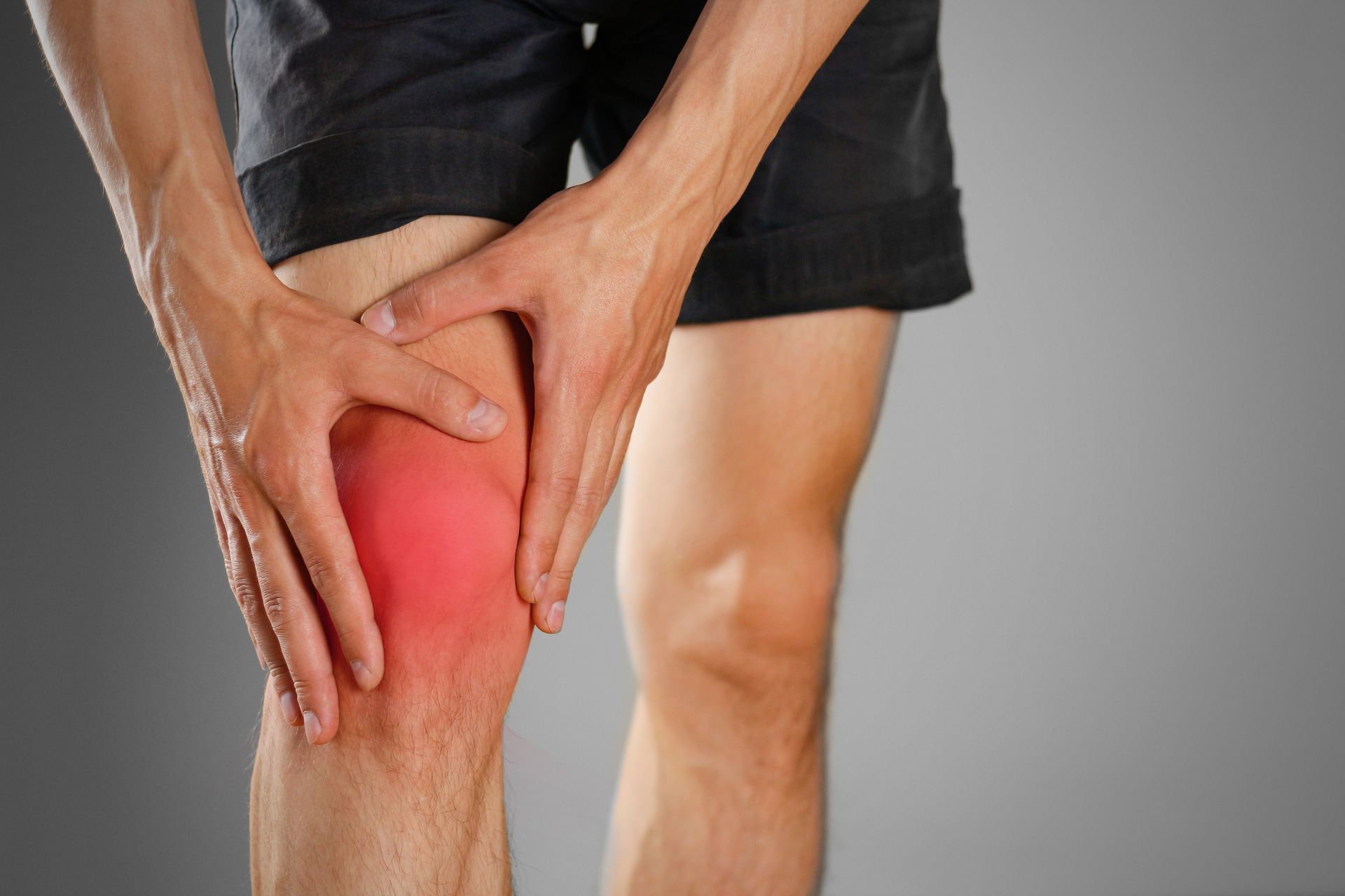Person holding knee, which is red, indicating pain; gray background.