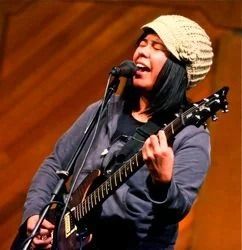 Person singing and playing electric guitar, wearing a knitted hat.