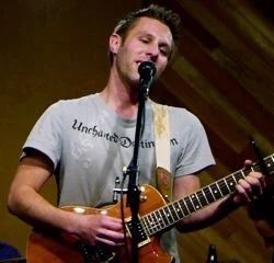 Man singing, playing guitar, grey