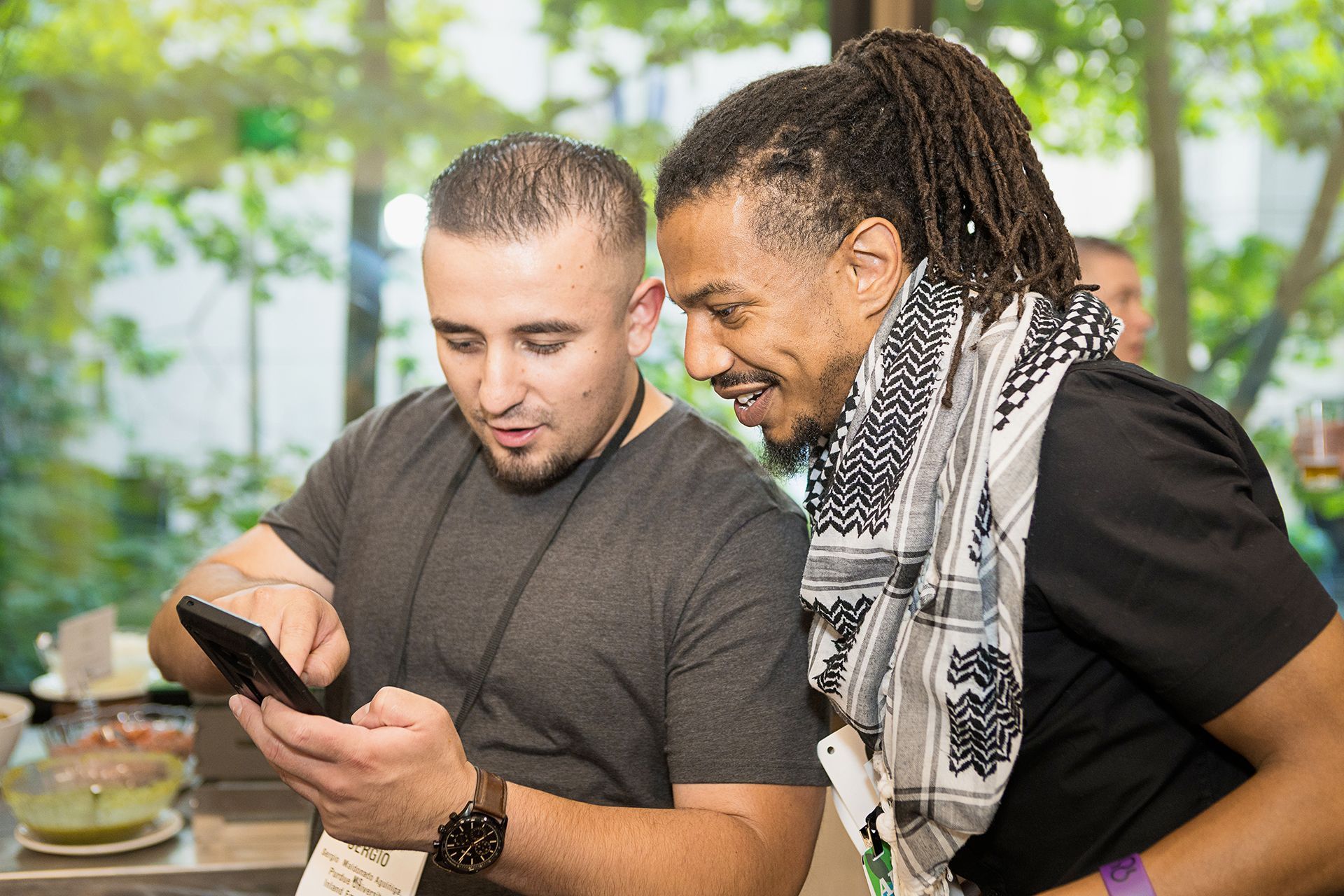 Two men are looking at a cell phone together.