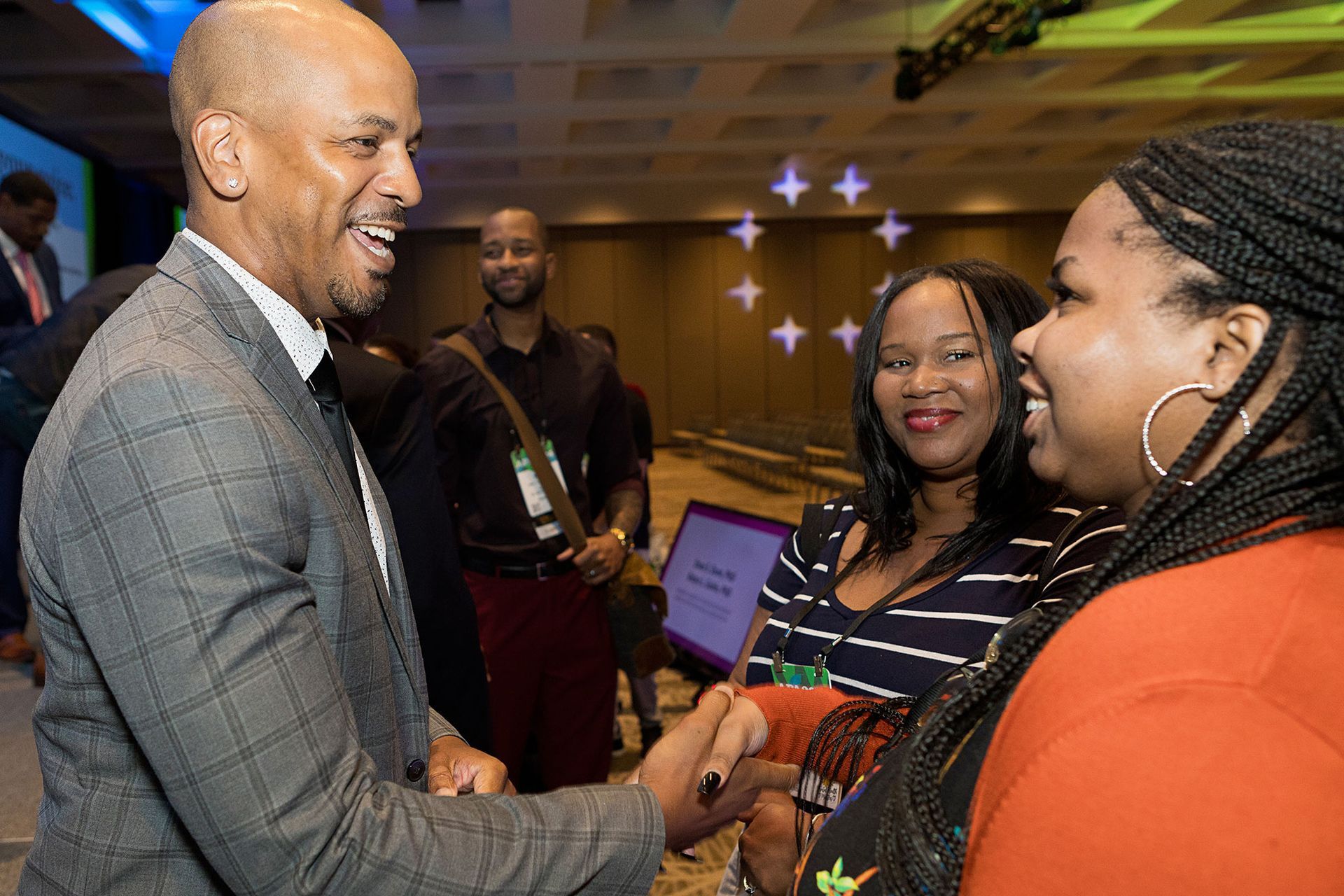 A man in a suit is shaking hands with a woman at a conference.