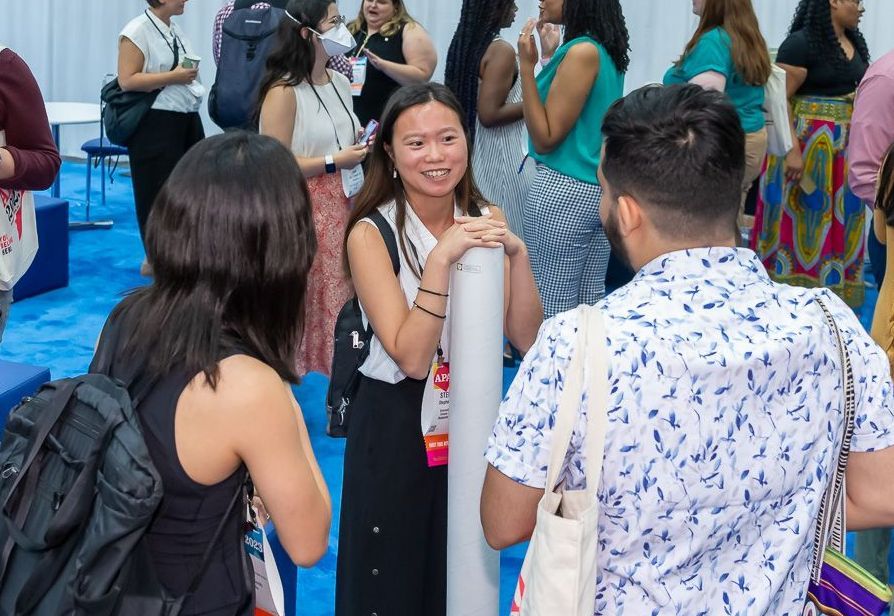 Two attendees take a photo in front of a selfie wall. 