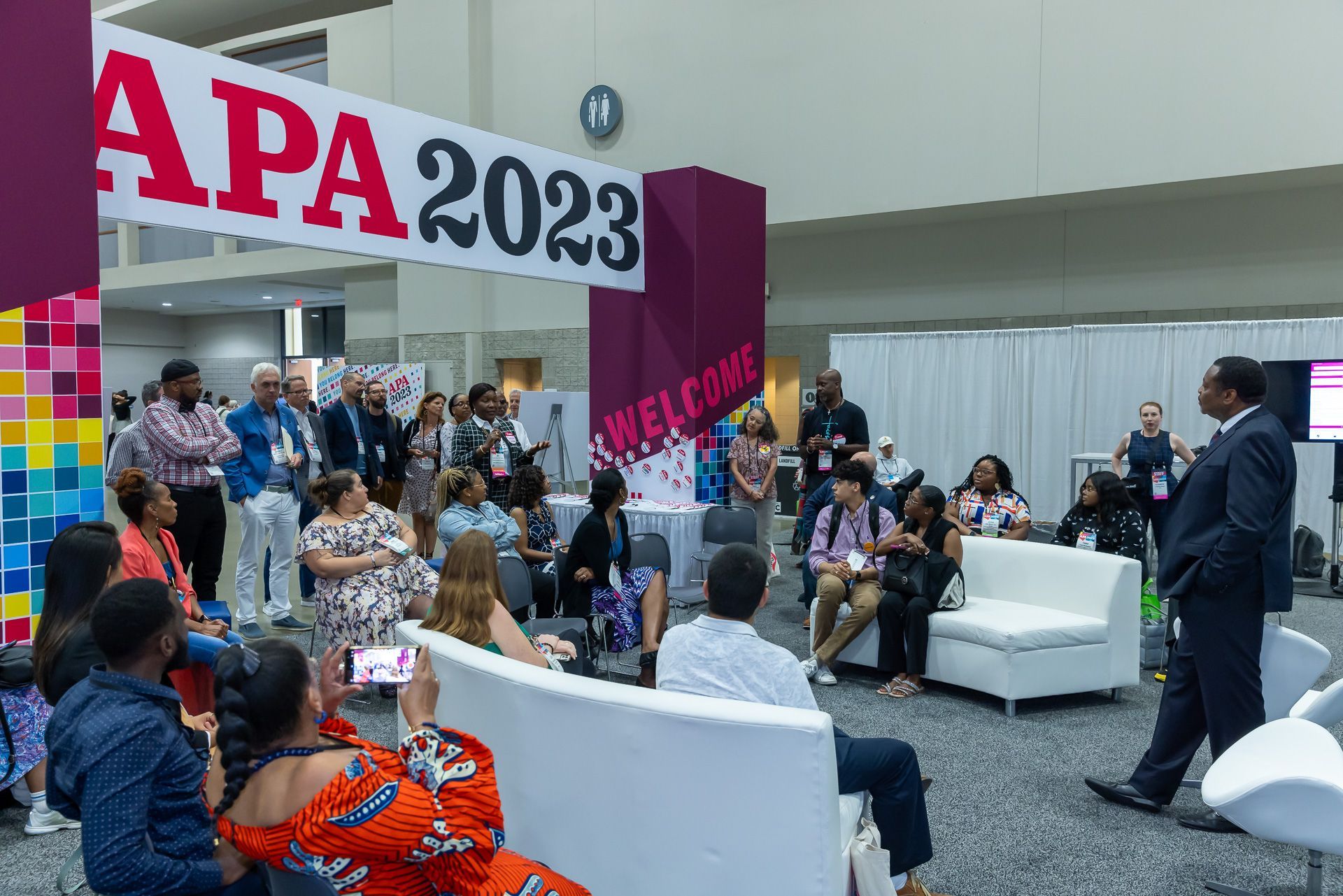 A group of people are sitting in a room under a sign that says apa 2023.