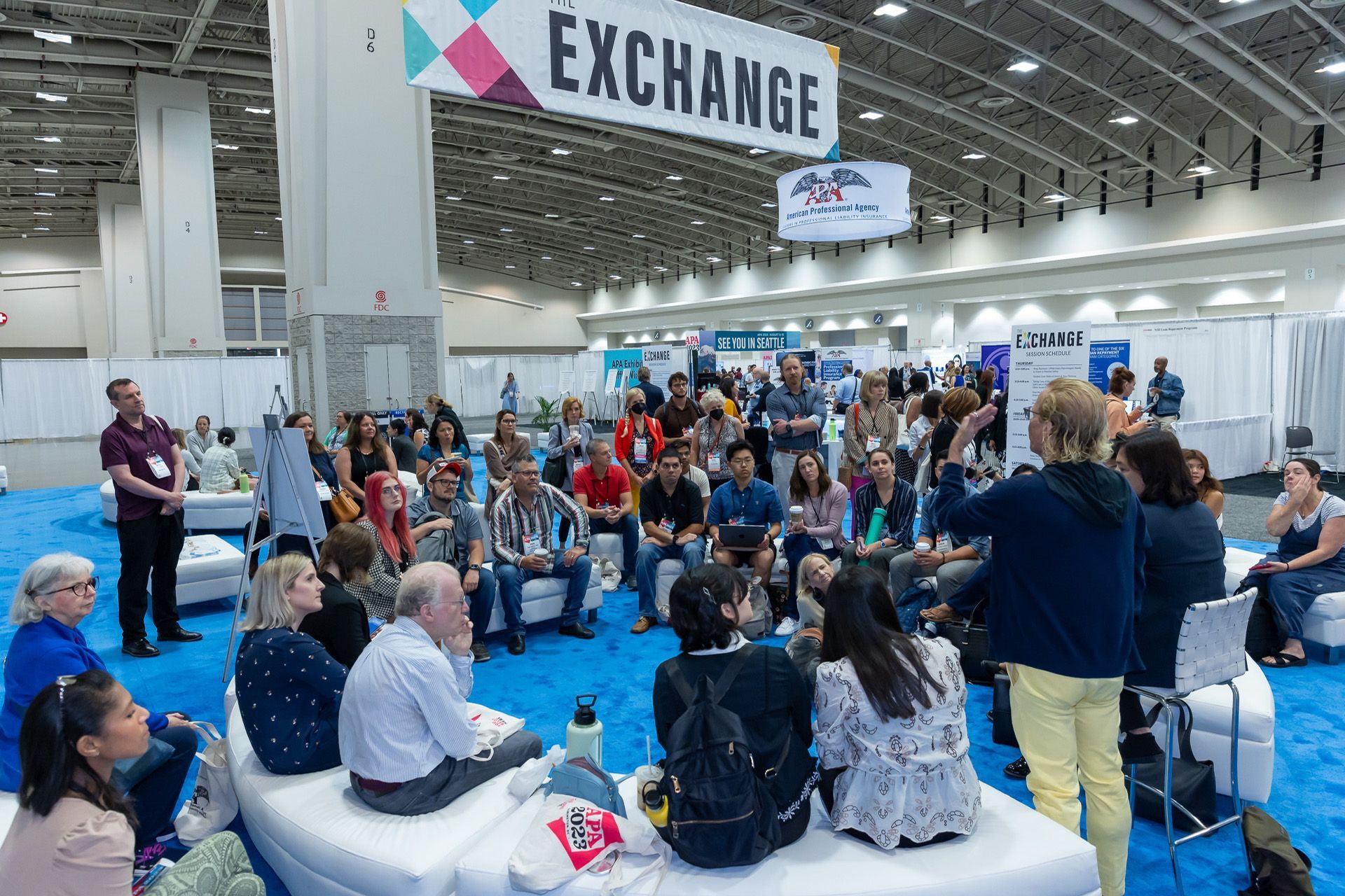 A group of people are sitting in a room under a sign that says exchange.