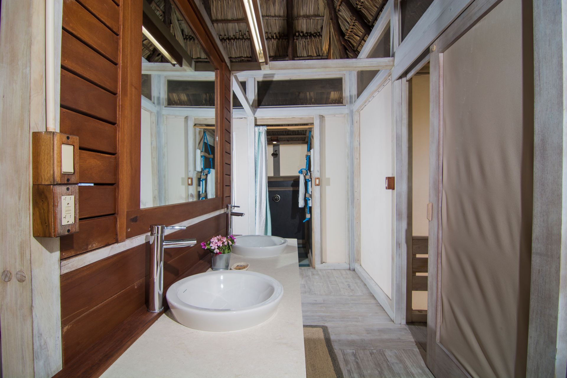 Bathroom with a white sink, brown wood trim, a large mirror, and sliding doors.
