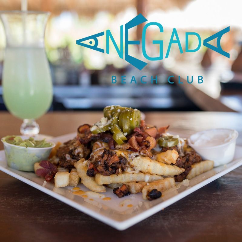 Negada Beach Club: plate of loaded fries with sides, drink in glass.