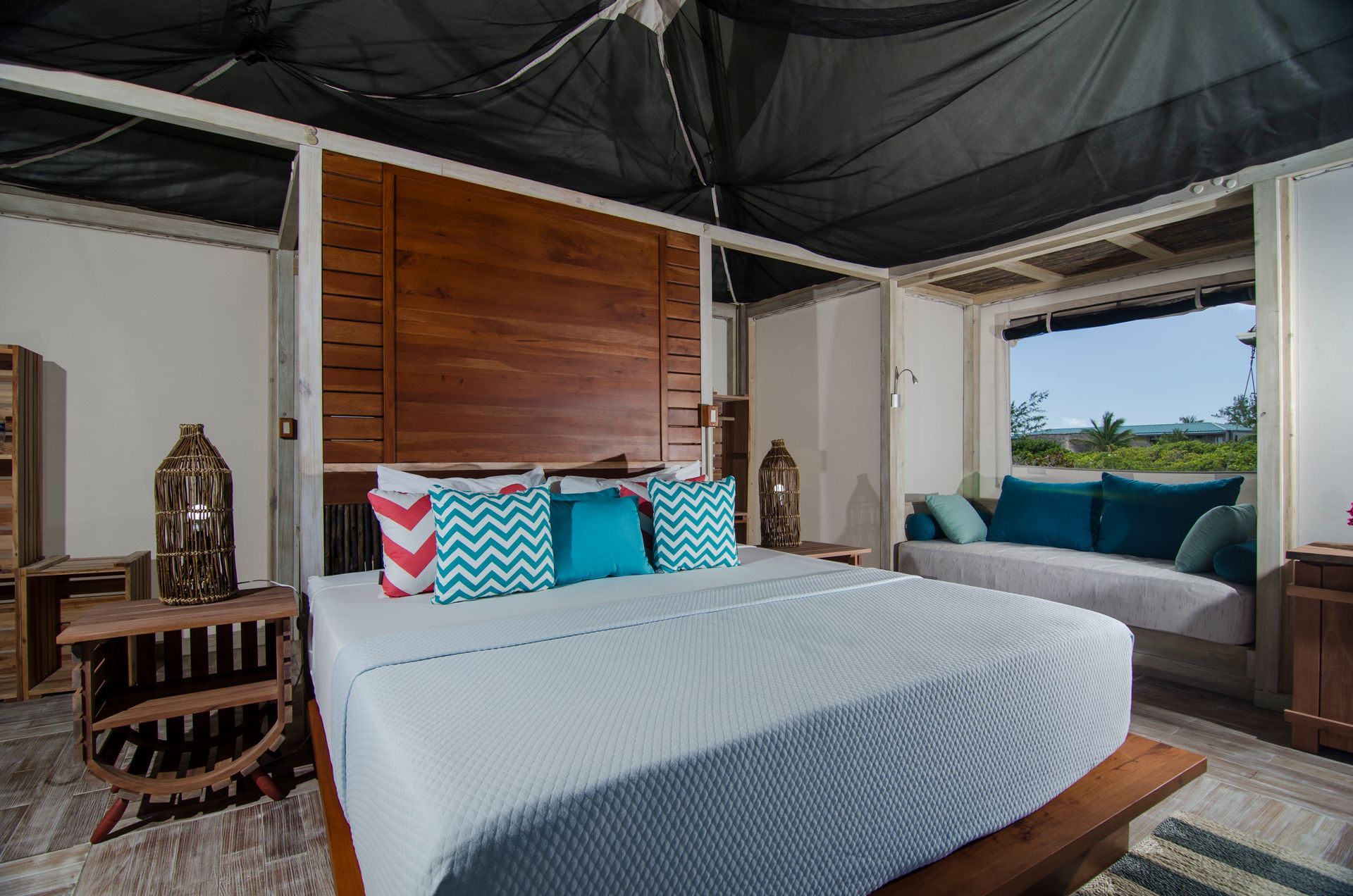 Bedroom with a large bed, wooden headboard, and a window seat overlooking the ocean.