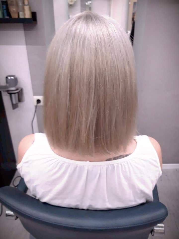 Eine Frau mit blonden Haaren sitzt in einem Stuhl in einem Salon.