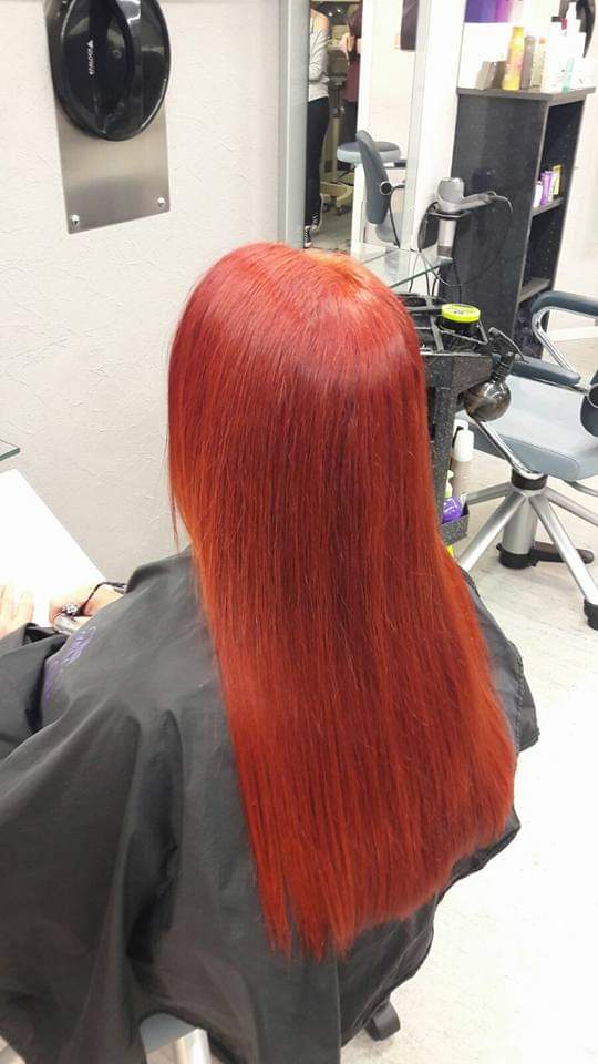 Eine Frau mit roten Haaren sitzt in einem Stuhl in einem Salon.