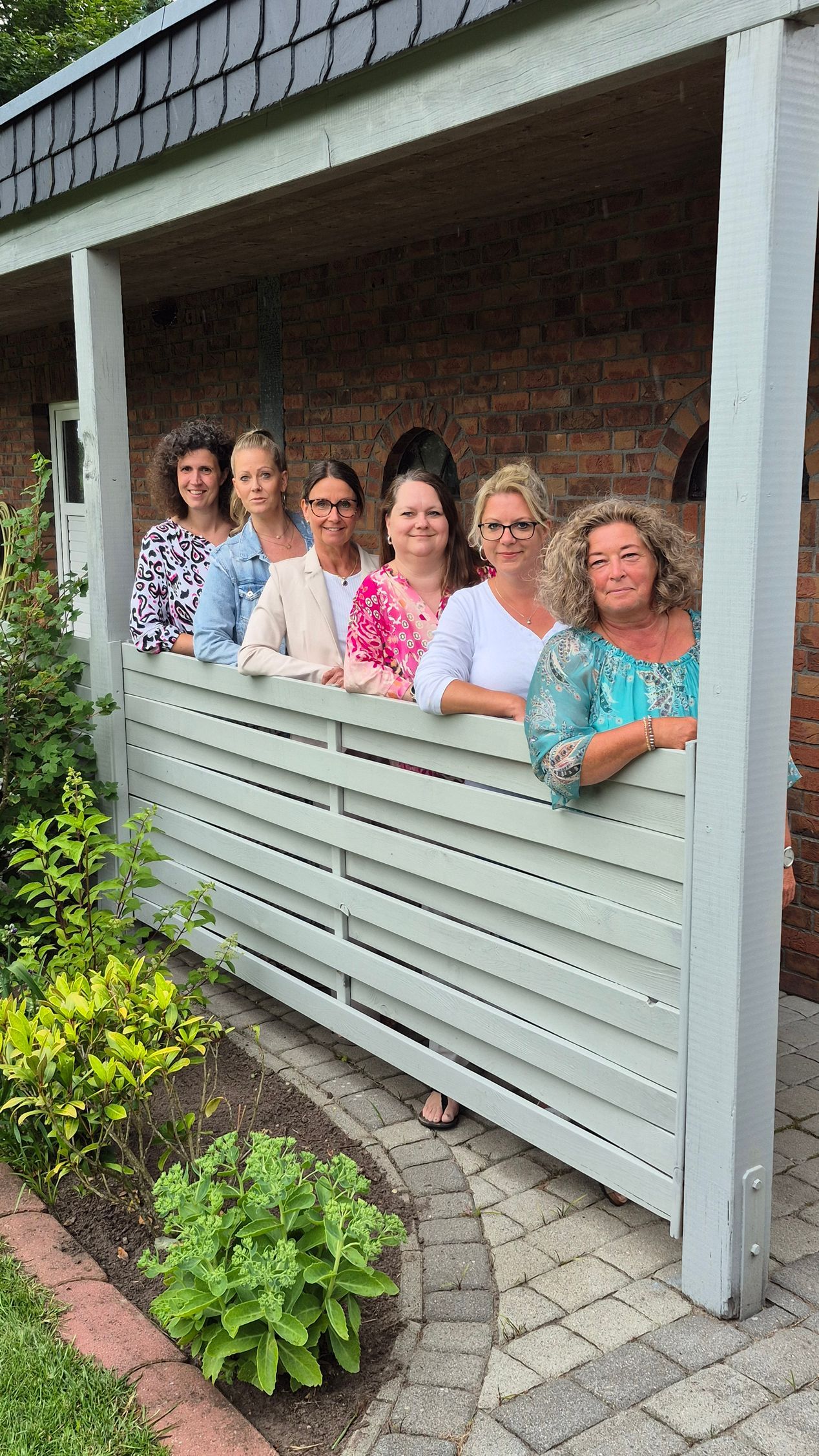Eine Gruppe von Frauen steht nebeneinander auf einer Veranda.