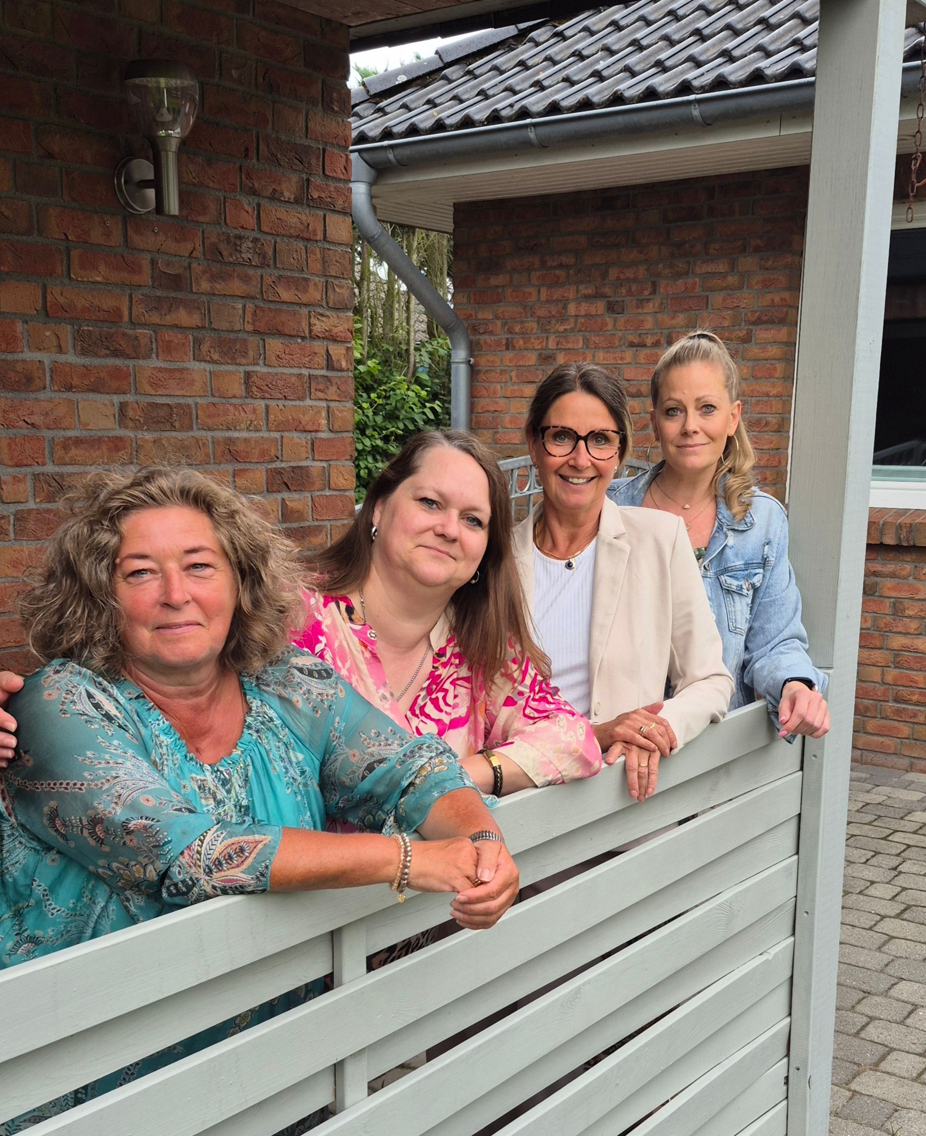 Eine Gruppe von Frauen steht nebeneinander auf einer Veranda.