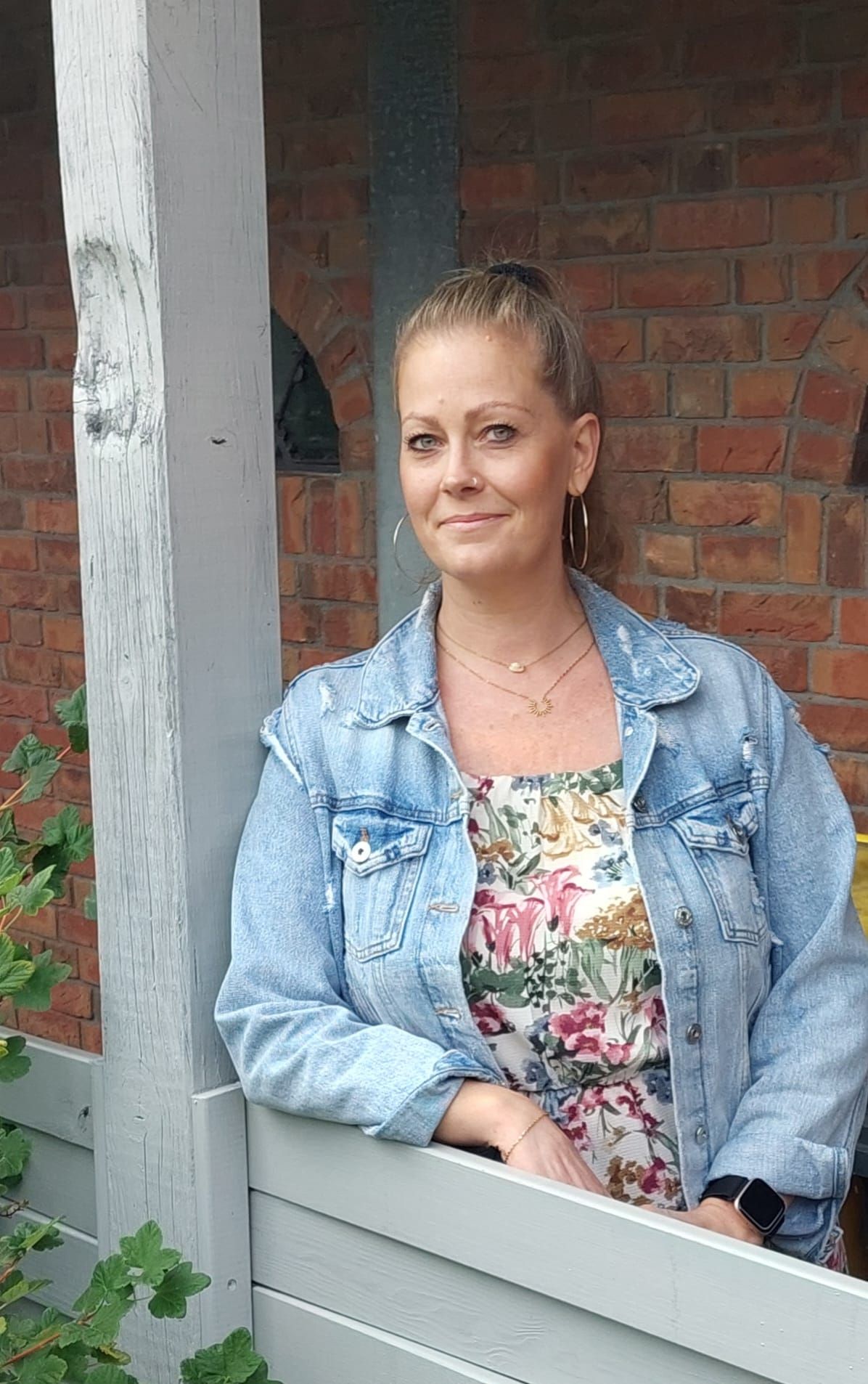 Auf einem Schwarzweißfoto sitzt eine Frau mit langen Haaren auf einem Stuhl und lächelt.