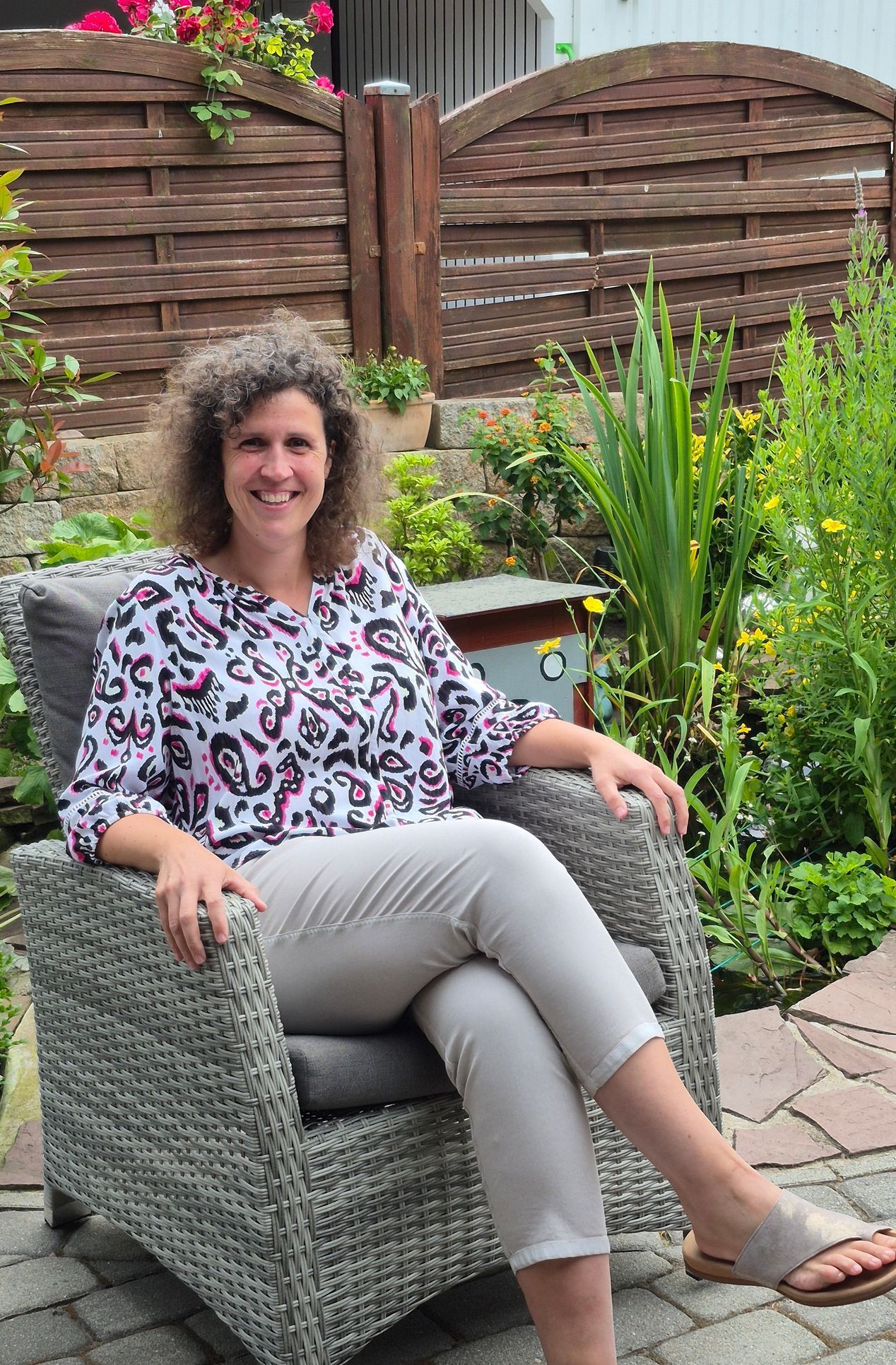 Eine Frau sitzt auf einem Stuhl in einem Garten.