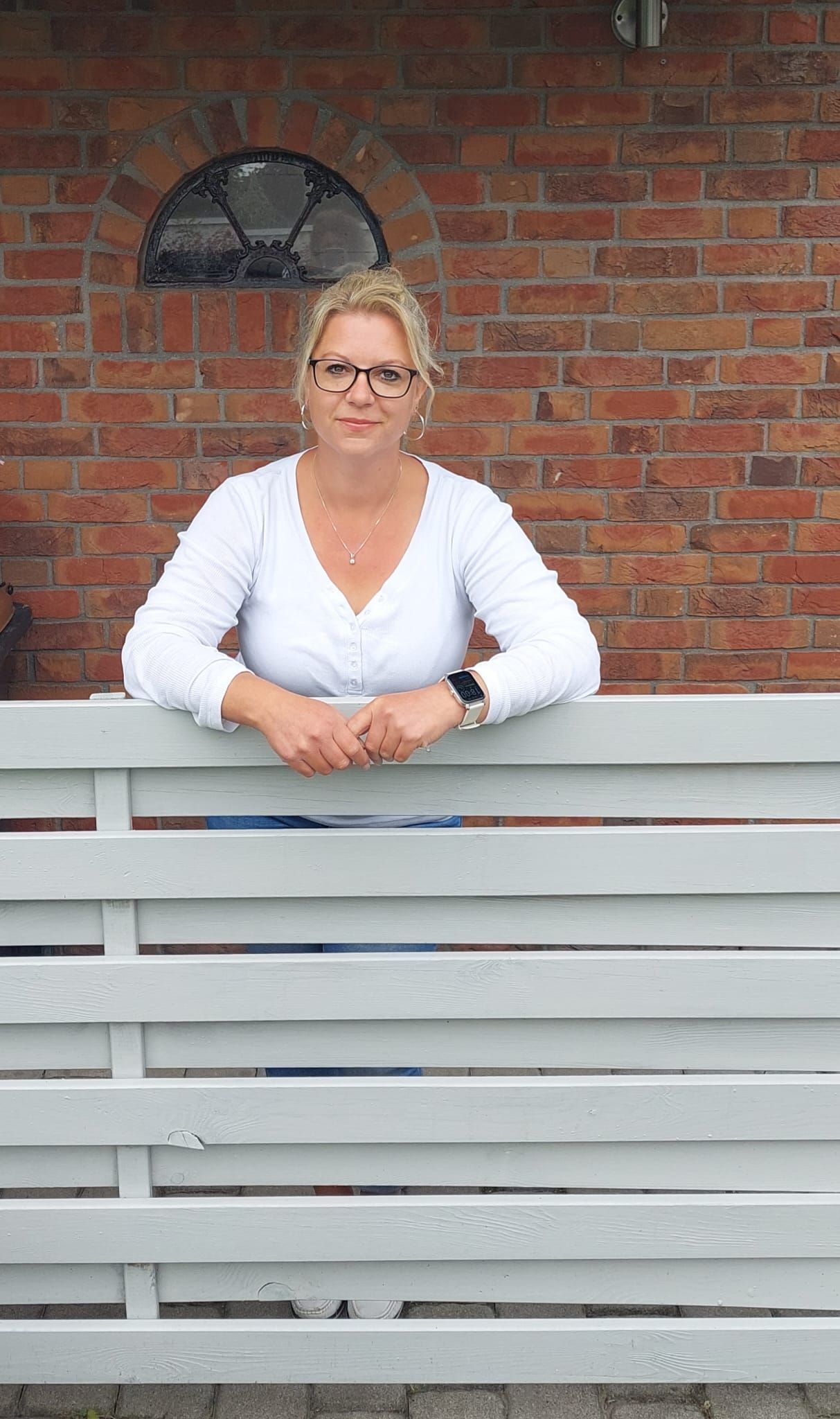 Ein Schwarzweißfoto einer Frau mit Brille und Halskette.