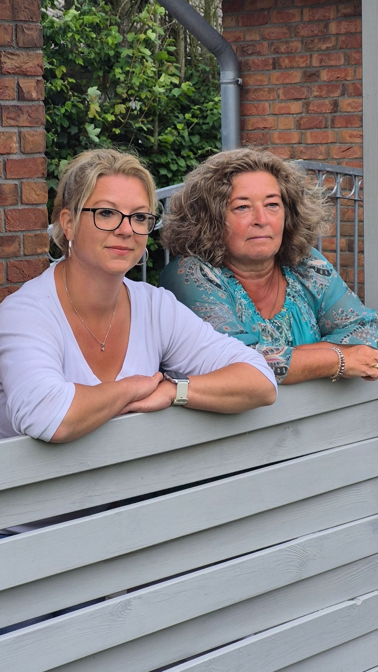 Zwei Frauen lehnen an einem Holzzaun.