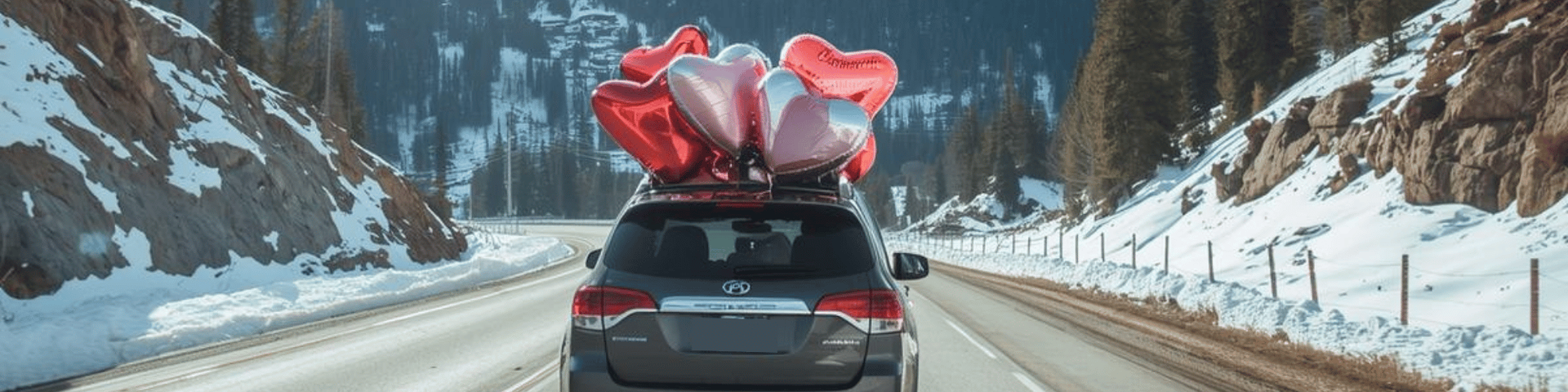 Toyota minivan driving on a snowy mountain road with heart balloons on the roof.
