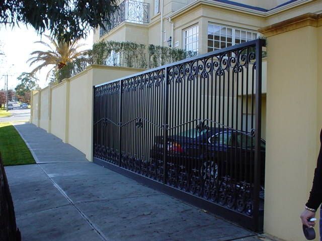 A black car is parked behind a wrought iron gate