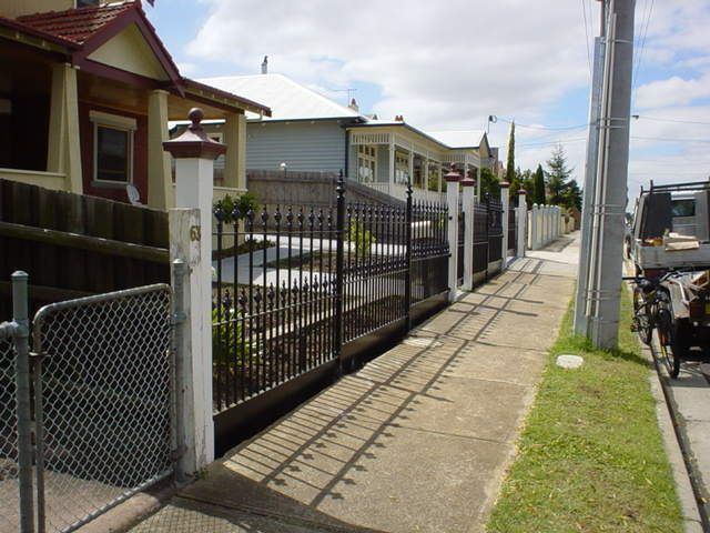A chain link fence along a sidewalk in front of a house