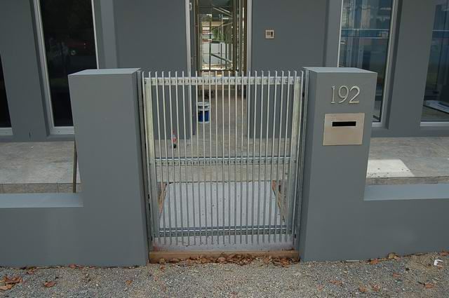 A fence with a gate and a mailbox in front of a house.