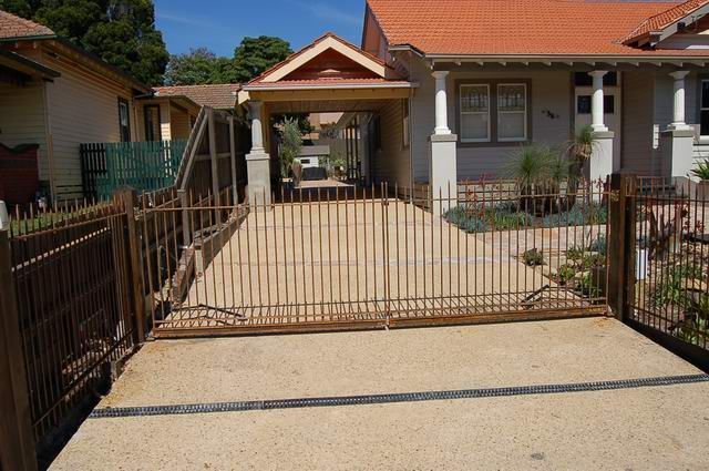 A driveway leading to a house with a fence around it.