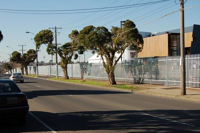 A car is driving down a street next to a fence