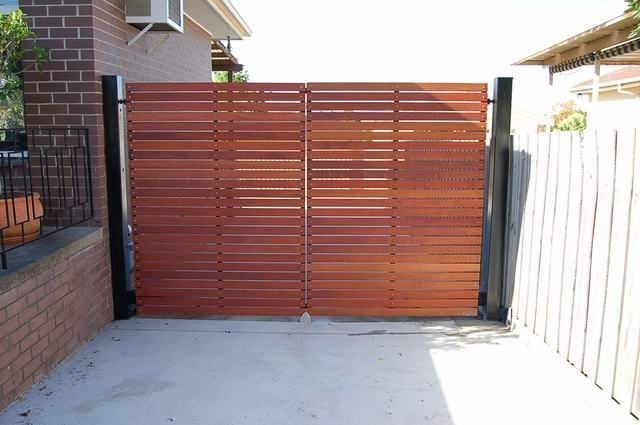 A wooden gate is open in front of a brick building