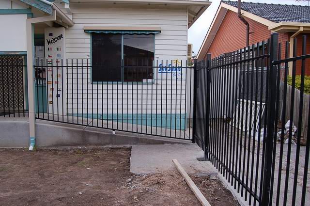 A black fence surrounds a house with a ramp in front of it