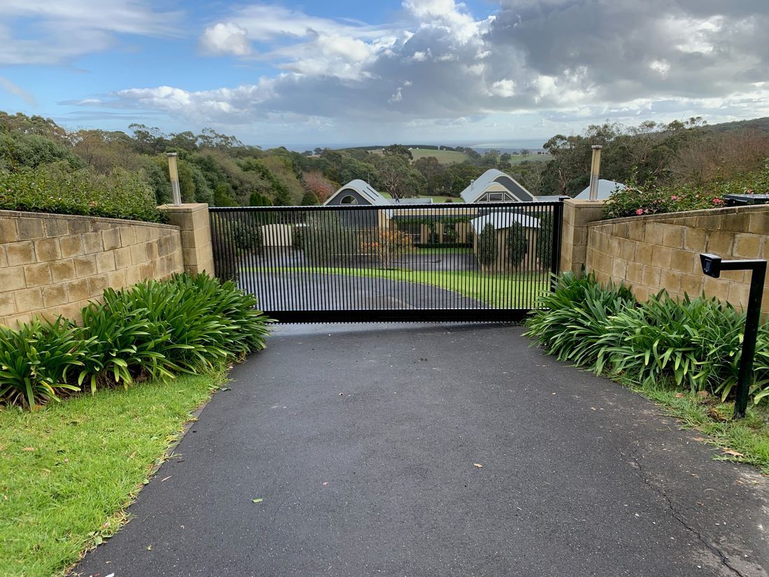 A driveway with a gate leading to a house