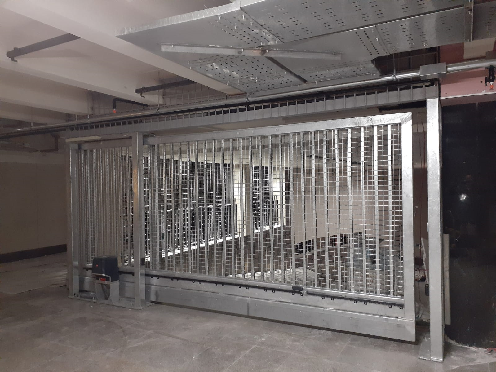 A sliding gate is open to a dirt road