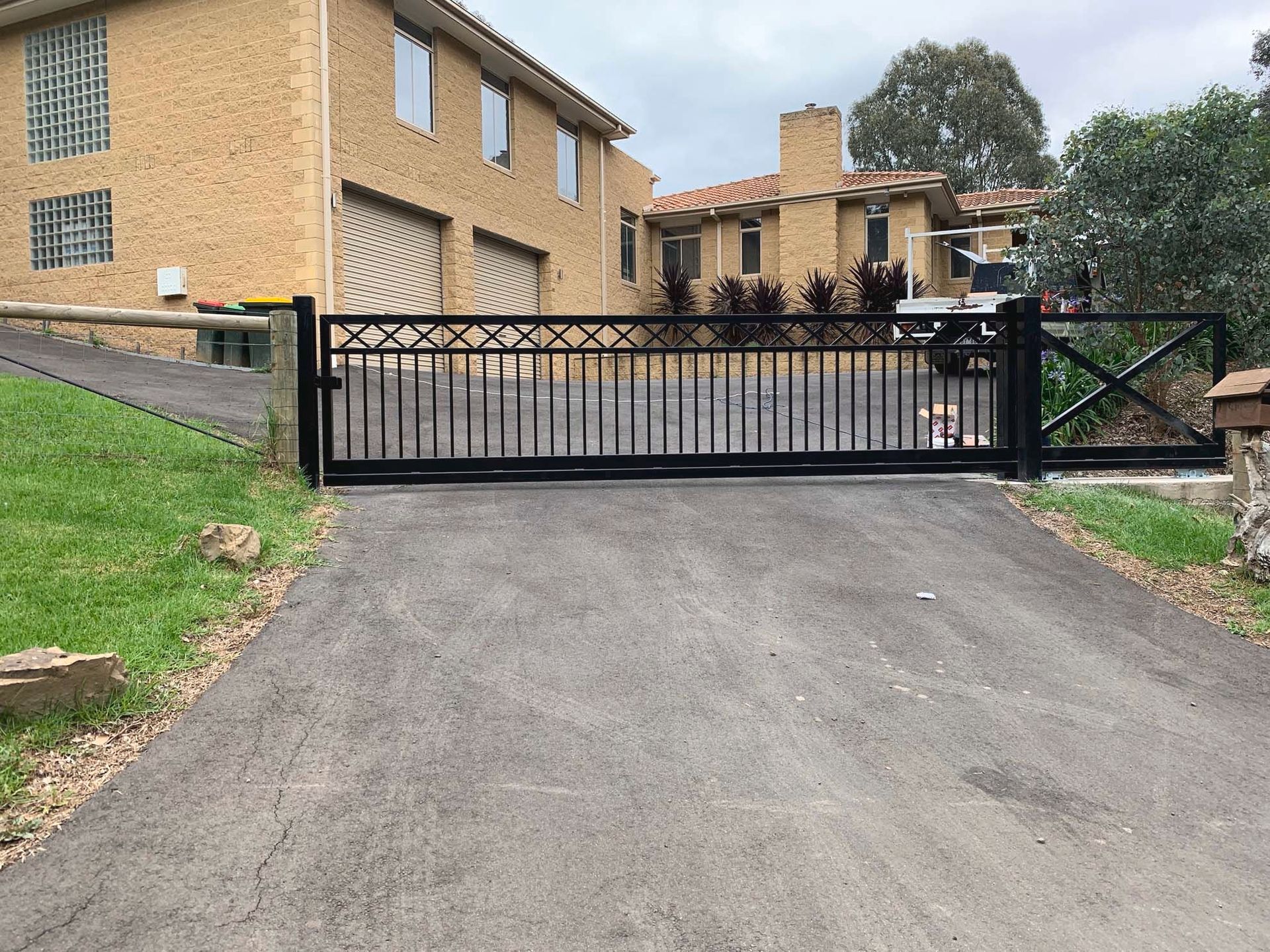 A large brick house with a sliding gate in front of it.